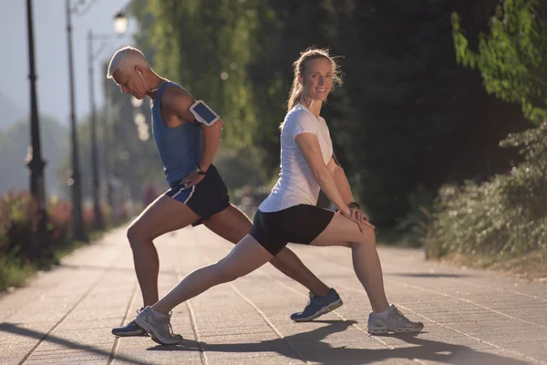 Paar warming up en stretching voor het joggen — Stockfoto