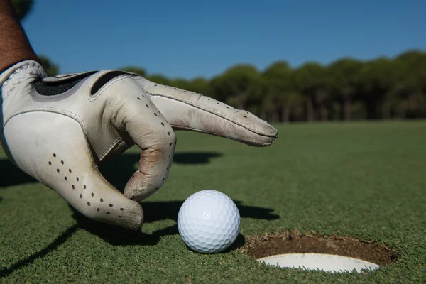 Mão do homem colocando bola de golfe no buraco — Fotografia de Stock