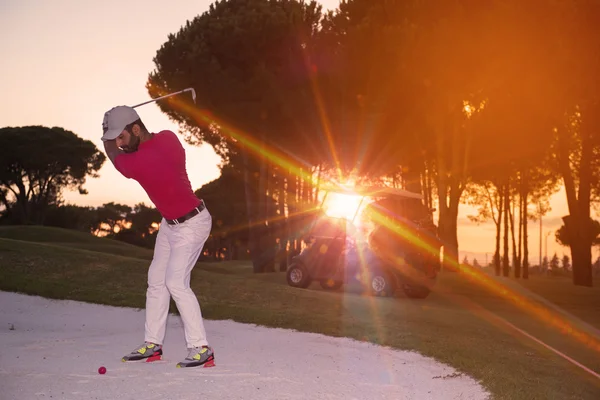 Golfista batendo um bunker de areia tiro no pôr do sol — Fotografia de Stock