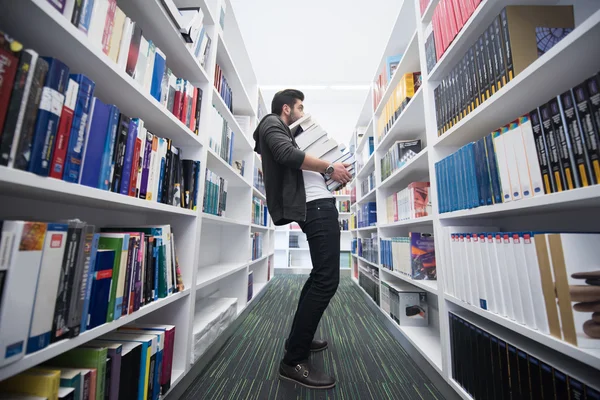 Student holding lot of books in school library — Stock Photo, Image