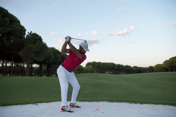 Golfer schlägt bei Sonnenuntergang in Sandbunker ein — Stockfoto