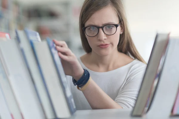 Portrait of famale student selecting book to read in library — Stock Photo, Image