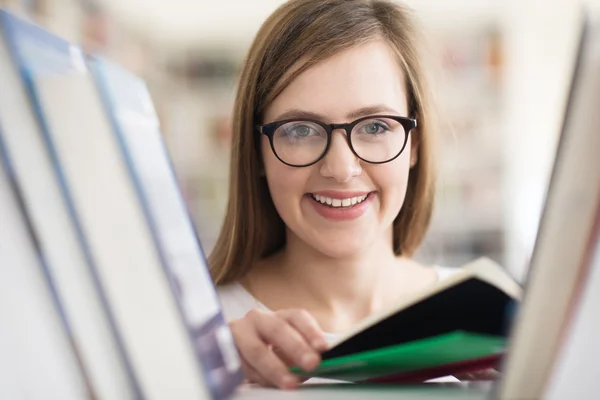 Portrait of famale student selecting book to read in library — Stock Photo, Image
