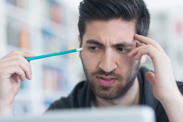 Estudiante en la biblioteca de la escuela usando el ordenador portátil para investigación —  Fotos de Stock