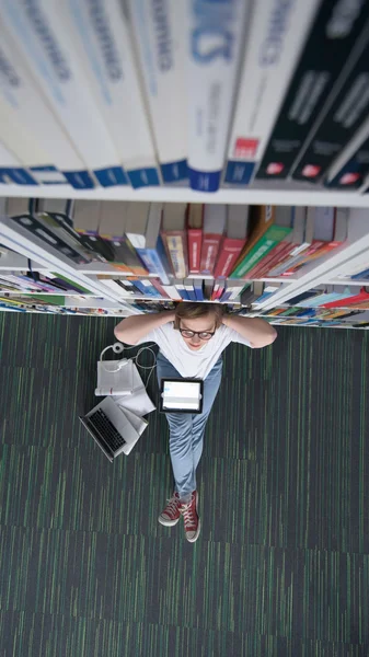 Studente donna studiare in biblioteca, utilizzando tablet e alla ricerca di — Foto Stock
