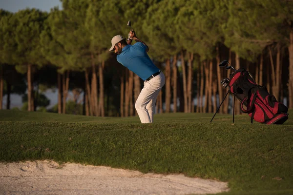 Golfista golpeando un tiro bunker de arena en la puesta del sol — Foto de Stock