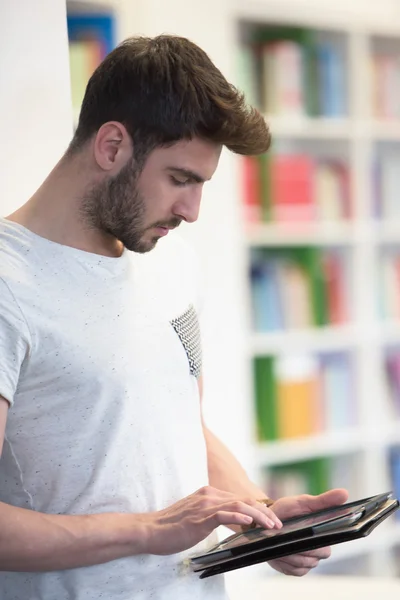 Estudiante en la biblioteca de la escuela usando tableta para la investigación — Foto de Stock