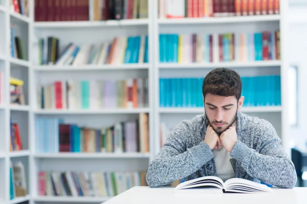 Retrato do estudante enquanto lê livro na biblioteca da escola — Fotografia de Stock