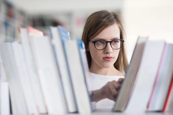 Portrait of famale student selecting book to read in library — Stock Photo, Image