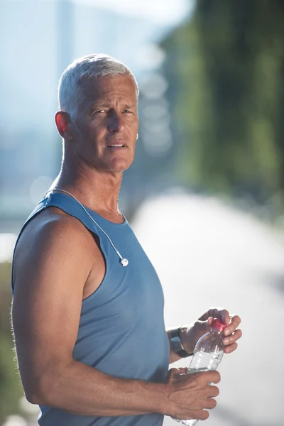 Senior jogging man drinking fresh water from bottle — Stock Photo, Image