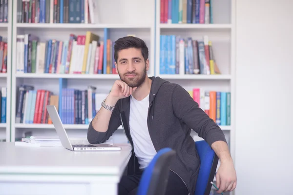 Estudiante en la biblioteca de la escuela usando el ordenador portátil para investigación — Foto de Stock