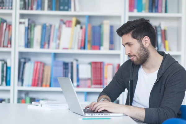 Studenten in de schoolbibliotheek met behulp van laptop voor onderzoek — Stockfoto