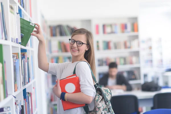 Famale estudante selecionando livro para ler na biblioteca — Fotografia de Stock