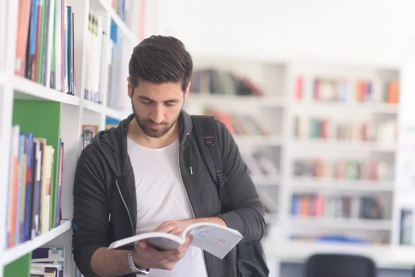 Retrato do estudante enquanto lê livro na biblioteca da escola — Fotografia de Stock