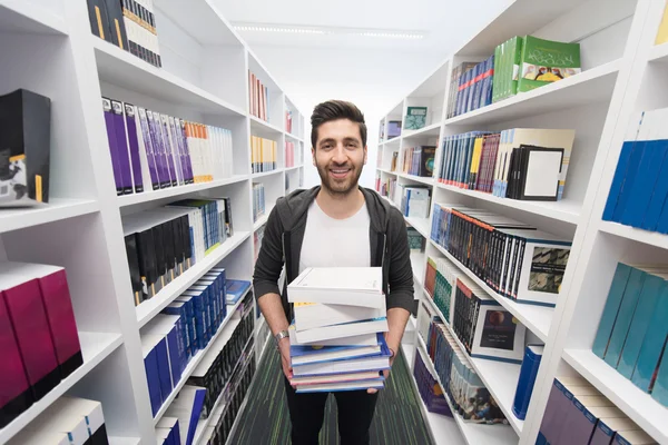 Estudiante sosteniendo muchos libros en la biblioteca de la escuela —  Fotos de Stock
