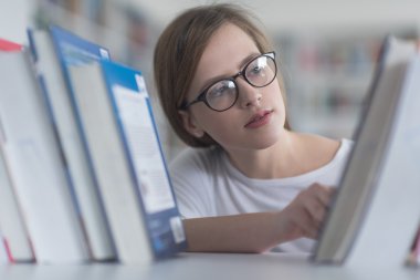 kitaplıkta okumak için kitap seçme famale öğrenci portresi