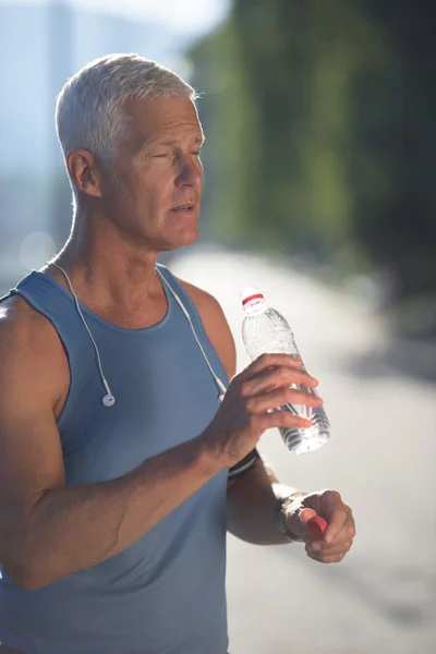 Homem de corrida sênior bebendo água doce de garrafa — Fotografia de Stock