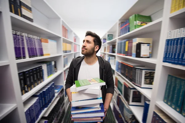 Étudiant tenant beaucoup de livres dans la bibliothèque de l'école — Photo