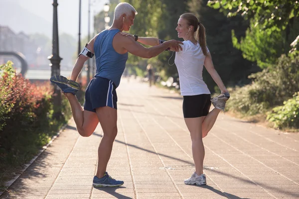 朝のランニング前にウォーミングアップやストレッチをしたり日の出を背景に街でトレーニングをしたり — ストック写真