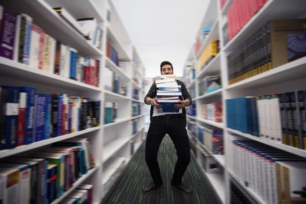 Φοιτητής κρατώντας πολλά βιβλία στη βιβλιοθήκη του σχολείου — Φωτογραφία Αρχείου