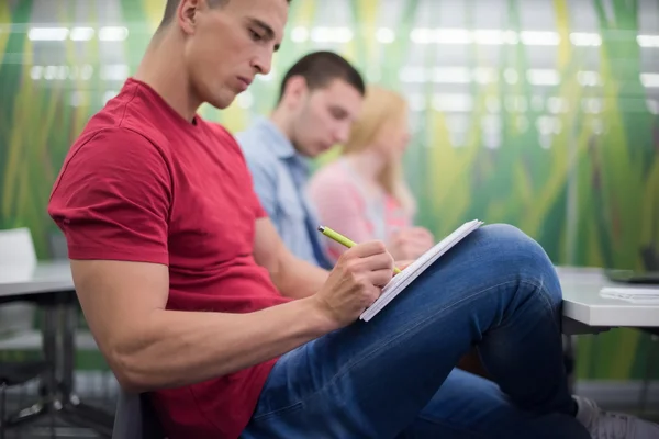 Estudante do sexo masculino tomar notas em sala de aula — Fotografia de Stock