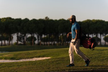 yürüyüş ve güzel günbatımı golf çantası taşıyan golfçü