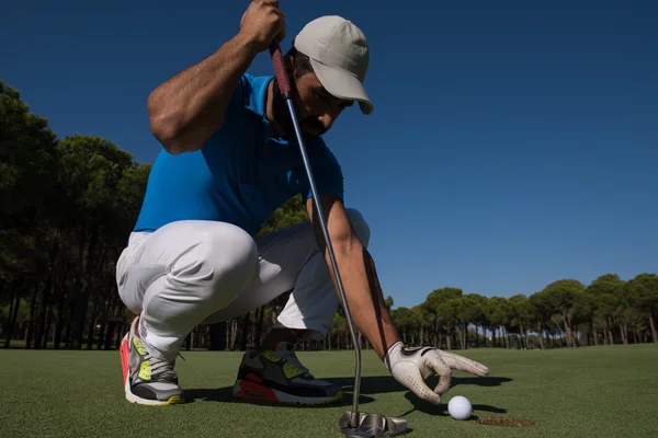 Main de l'homme mettant balle de golf dans le trou — Photo