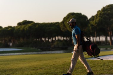 yürüyüş ve güzel günbatımı golf çantası taşıyan golfçü