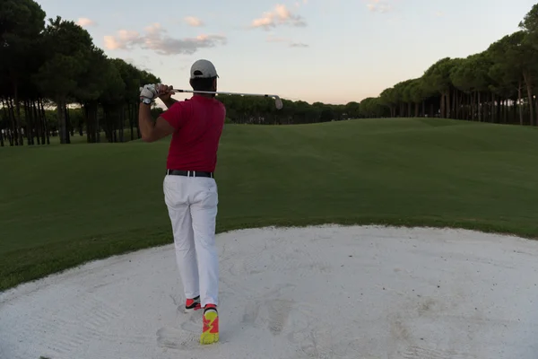 Golfer raken van een zand bunker shot op zonsondergang — Stockfoto