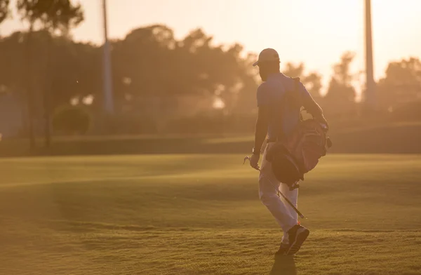 Golfista chůzi a nést brašnu na krásný západ slunce — Stock fotografie