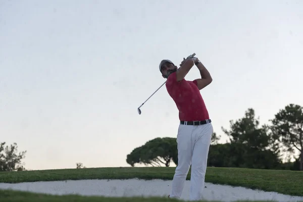 Golfista batendo um bunker de areia tiro no pôr do sol — Fotografia de Stock