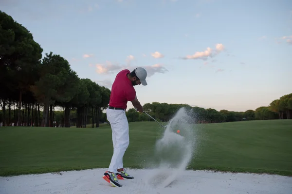 Golfista batendo um bunker de areia tiro no pôr do sol — Fotografia de Stock