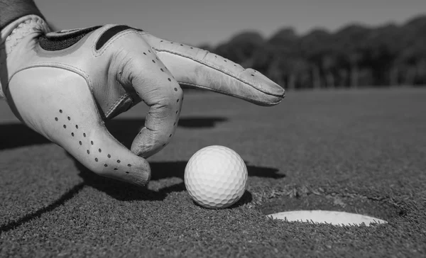 Mão do homem colocando bola de golfe no buraco — Fotografia de Stock