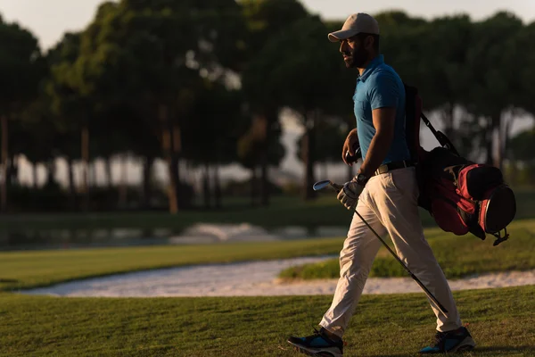 Golfista andando e carregando saco de golfe ao pôr do sol bonito — Fotografia de Stock