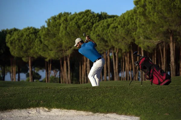 Golfspelare slår en sand bunker skott på sunset — Stockfoto