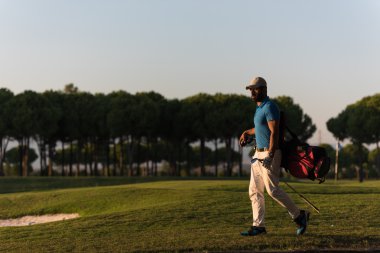 yürüyüş ve güzel günbatımı golf çantası taşıyan golfçü