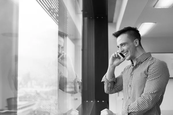 Jovem homem de negócios usando telefone inteligente no escritório — Fotografia de Stock