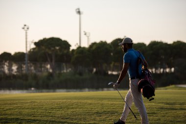 yürüyüş ve güzel günbatımı golf çantası taşıyan golfçü