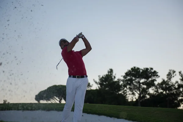 Golfer raken van een zand bunker shot op zonsondergang — Stockfoto