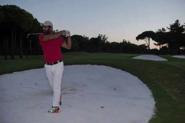 Golfista batendo um bunker de areia tiro no pôr do sol — Fotografia de Stock