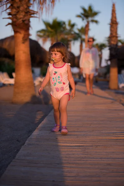 可爱的小宝贝女孩和母亲一起从海滩漫步在美丽的日落背景 — 图库照片
