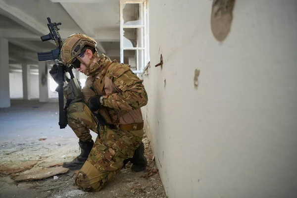 Soldado em ação perto de janela mudando revista e se abrigar — Fotografia de Stock