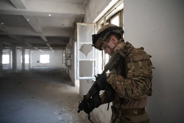Voják v akci poblíž okna měnící časopis a kryjte se — Stock fotografie