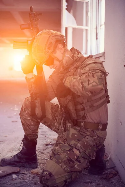 Voják v akci poblíž okna měnící časopis a kryjte se — Stock fotografie