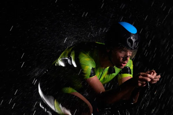 Triathlon idrottare rida cykel snabbt på regnig natt — Stockfoto