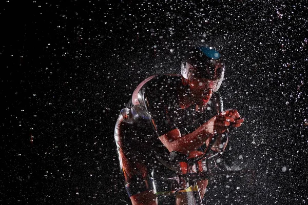 Triathlon atleta in sella alla bici veloce nella notte piovosa — Foto Stock