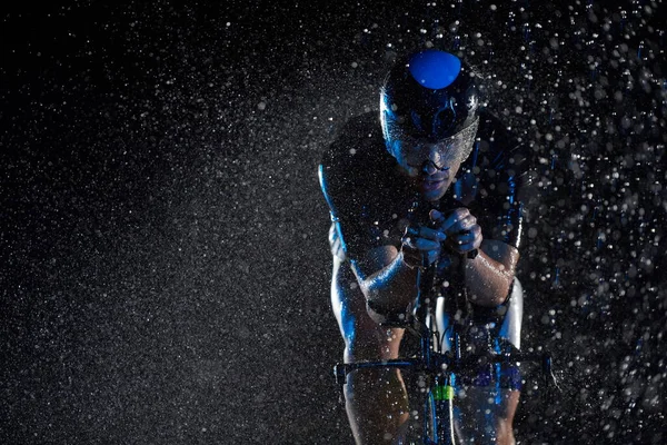 Triatlón atleta montar bicicleta rápido en la noche lluviosa —  Fotos de Stock