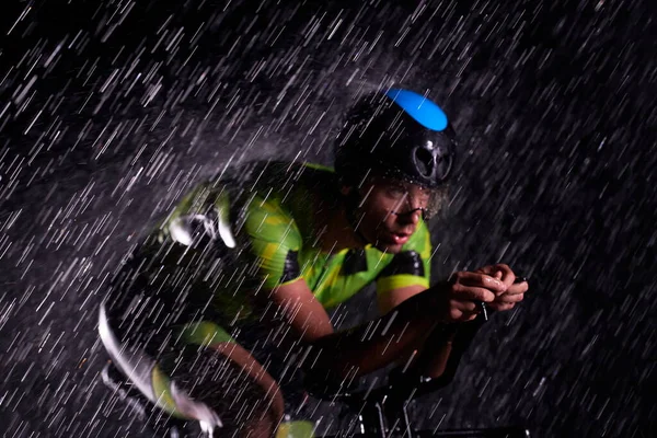 Triatlon atleet rijden fiets snel op regenachtige nacht — Stockfoto