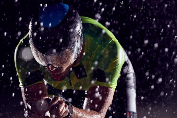 Triathlon atleta in sella alla bici veloce nella notte piovosa — Foto Stock