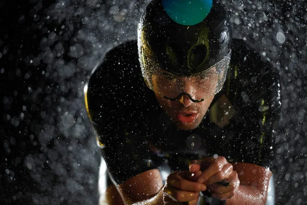 Triatlón atleta montar bicicleta rápido en la noche lluviosa —  Fotos de Stock